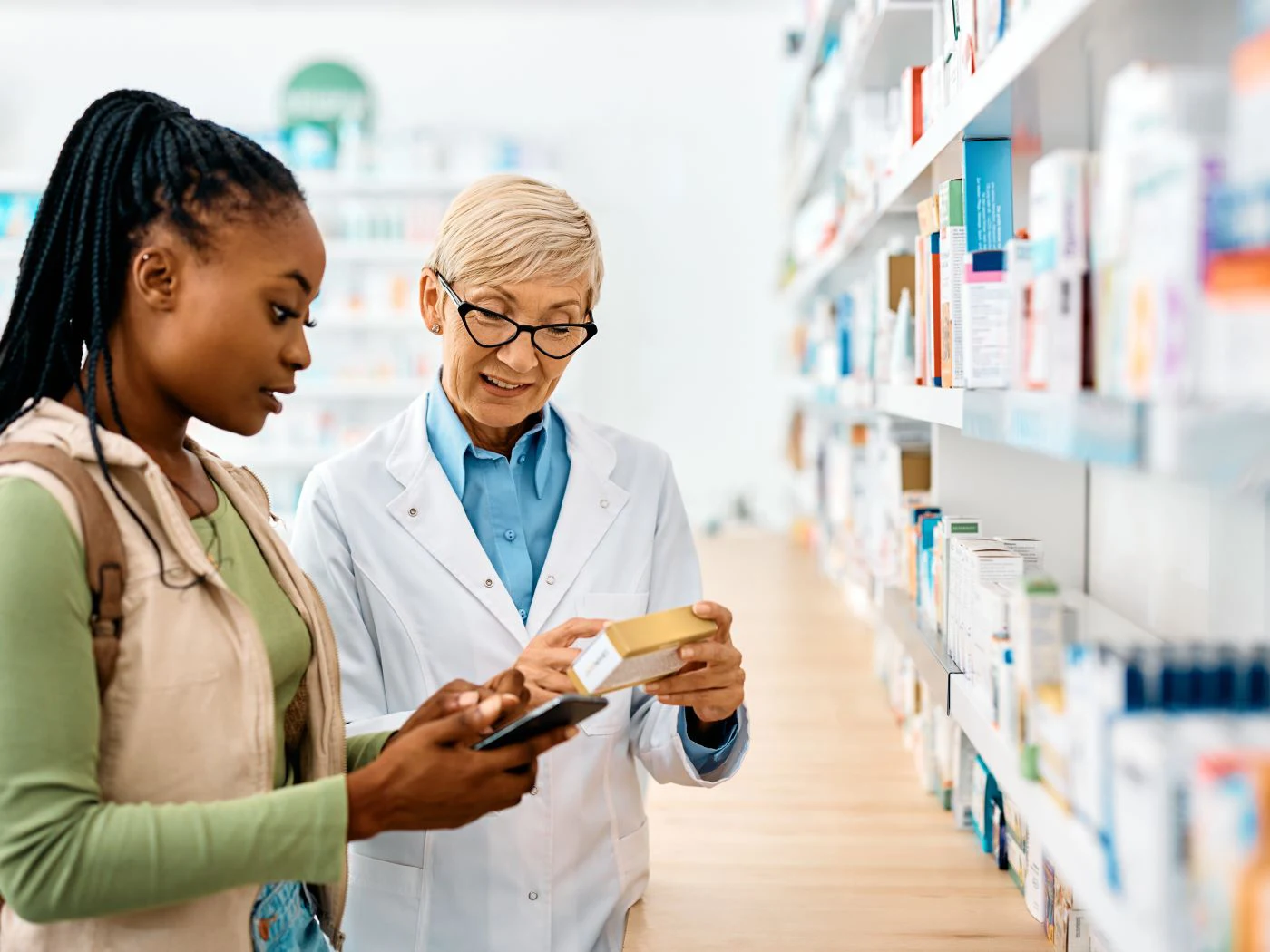 Un farmacéutico le muestra información a una mujer sobre una receta.