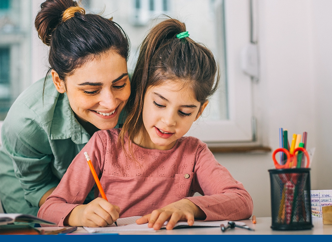 woman happily helping her young daughter with her homework