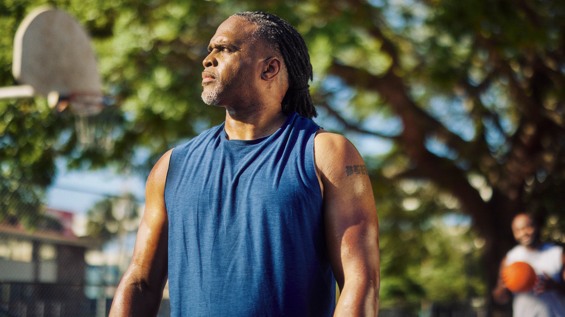 man looking into the sun while playing backetball with community