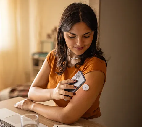 woman checking her blood glucose using her smart phone and wearable bloods glucose monitor