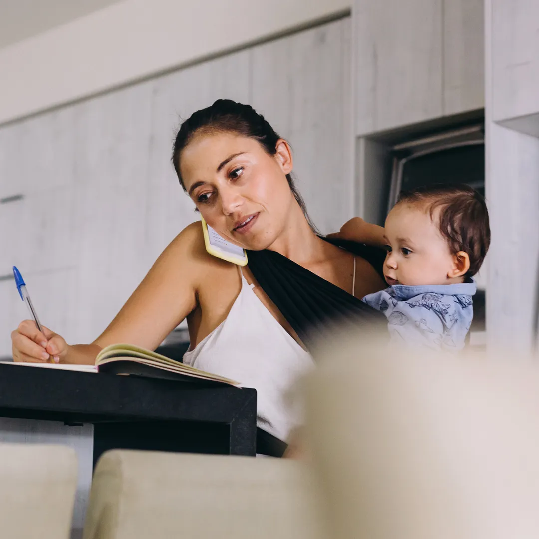 busy mother multitasking, talking to a Florida Blue agent while taking care of her toddler