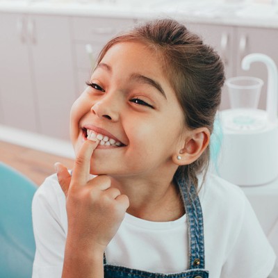 niño pequeño señalando sus dientes limpios después de una visita al dentista