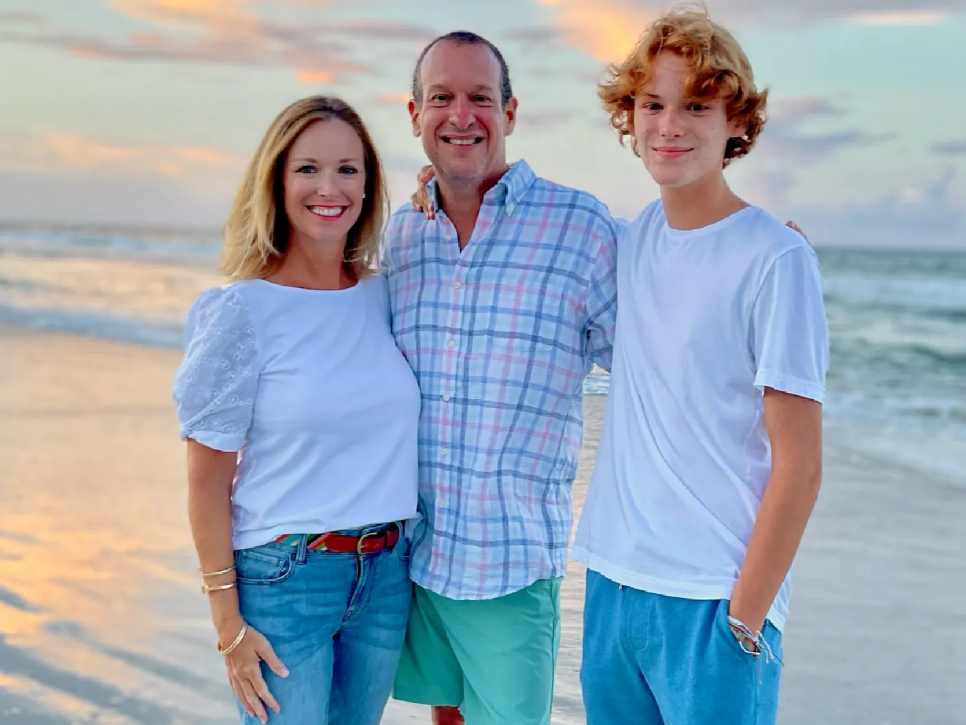 Family posing for photo on beach, highlighting the members story about beating cancer