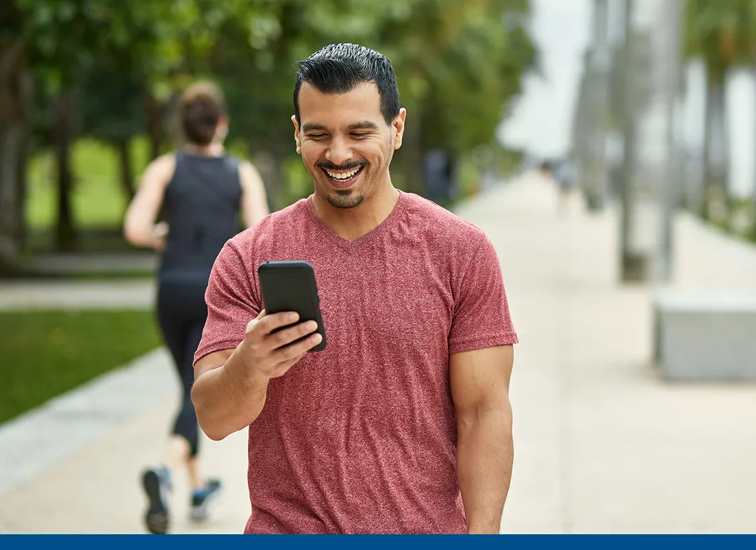 man looking at Florida Blue plans on his phone while walking in a park