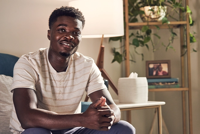 man sitting on couch with his hands together