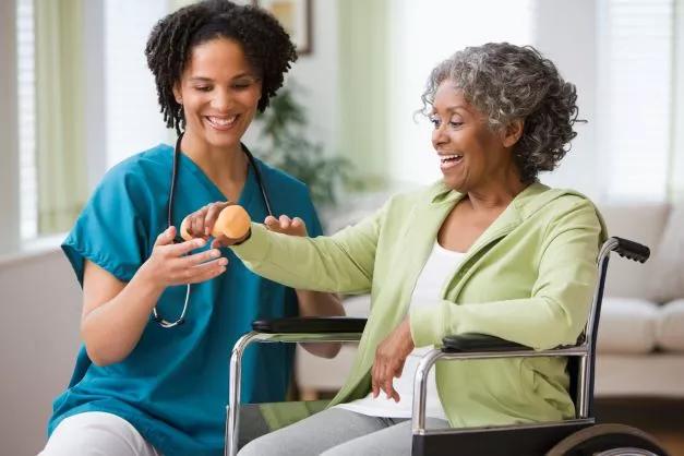 Nurse helps woman in wheelchair to exercise